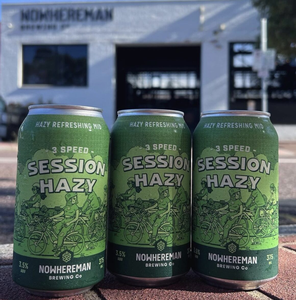 Three cans of Nowhereman's craft beer session hazy in front of their Perth brewery